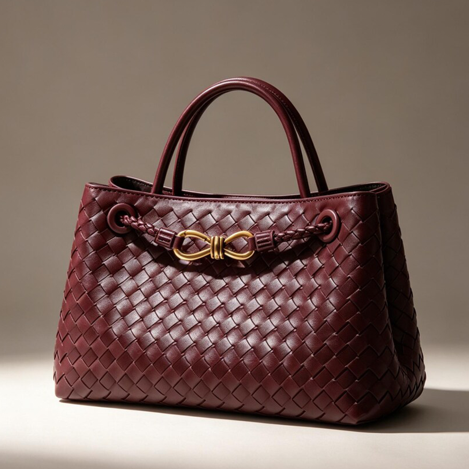 Intricate Woven Compact Satchel With Gold Infinity Metal Embellishment, Matching Curved Top Grips And Soft Structured Rectangular Silhouette